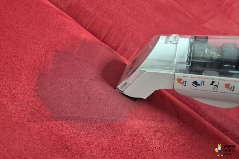 Der Shark Stainforce Akku-Fleckenreiniger saugt mit Bürstenaufsatz einen Fleck aus einem Sofa.